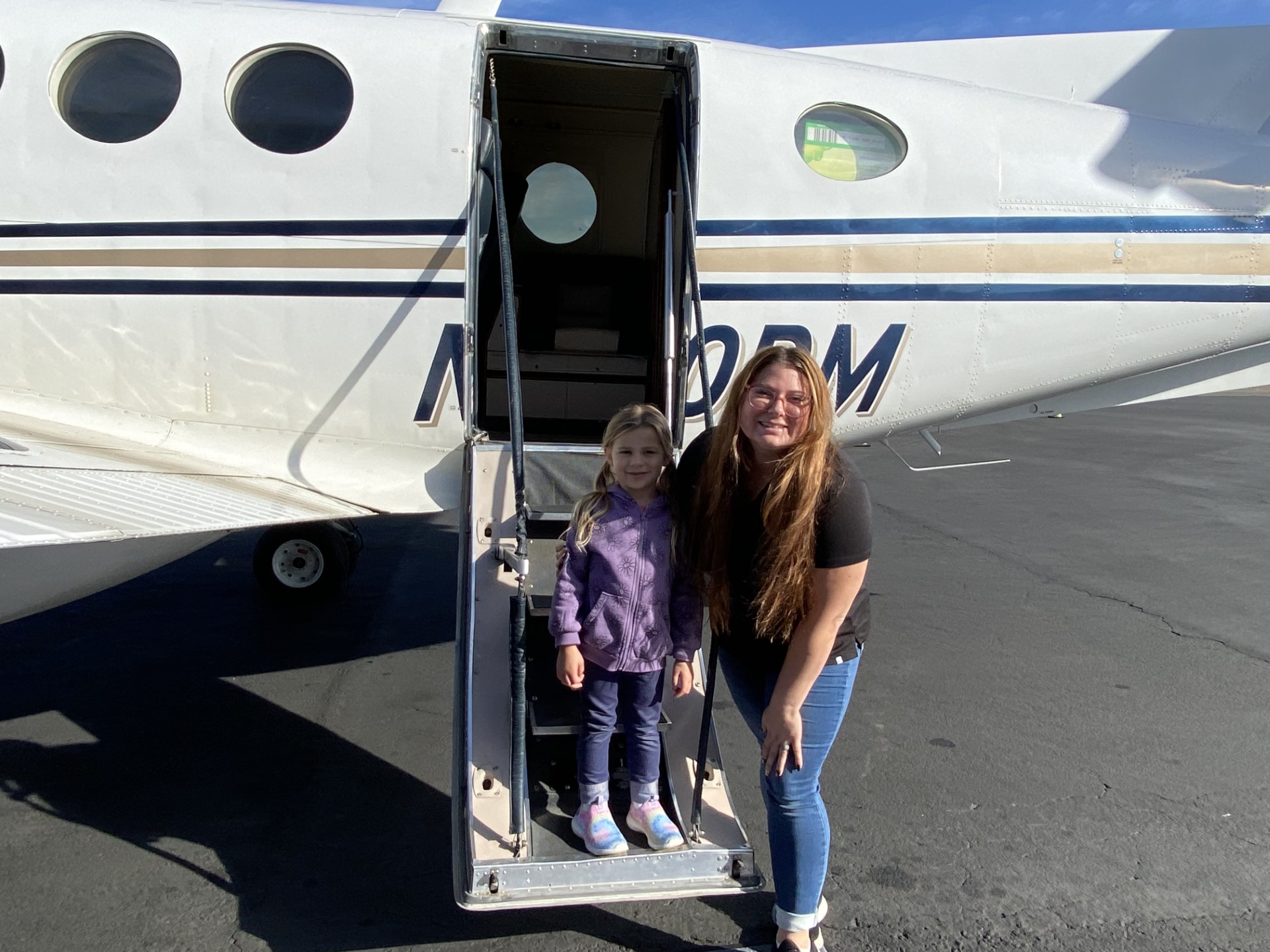 Sarah Tanis and her daughter standing on the steps of an airplane.