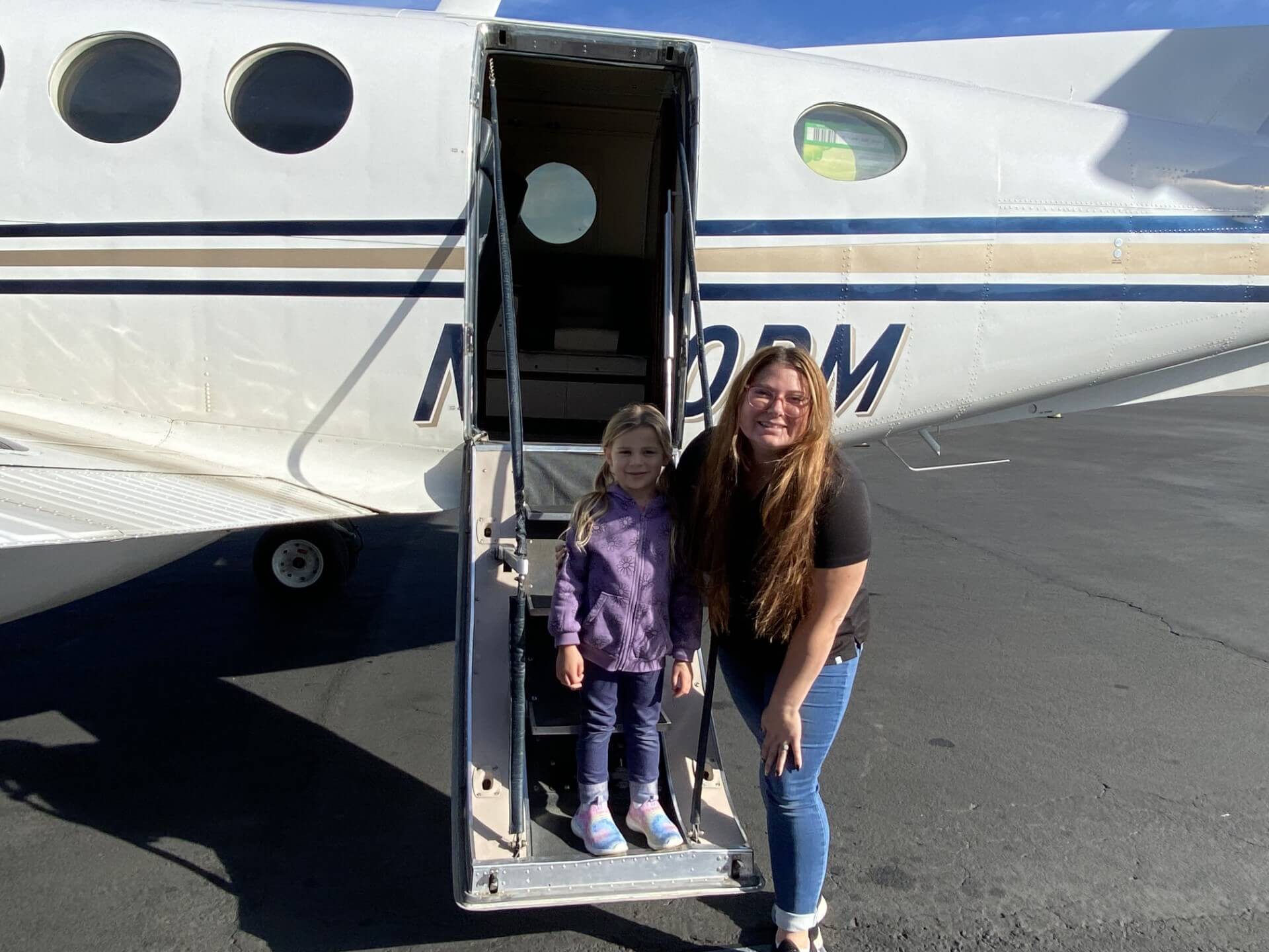 Sarah Tanis and her daughter standing on the steps of an airplane.